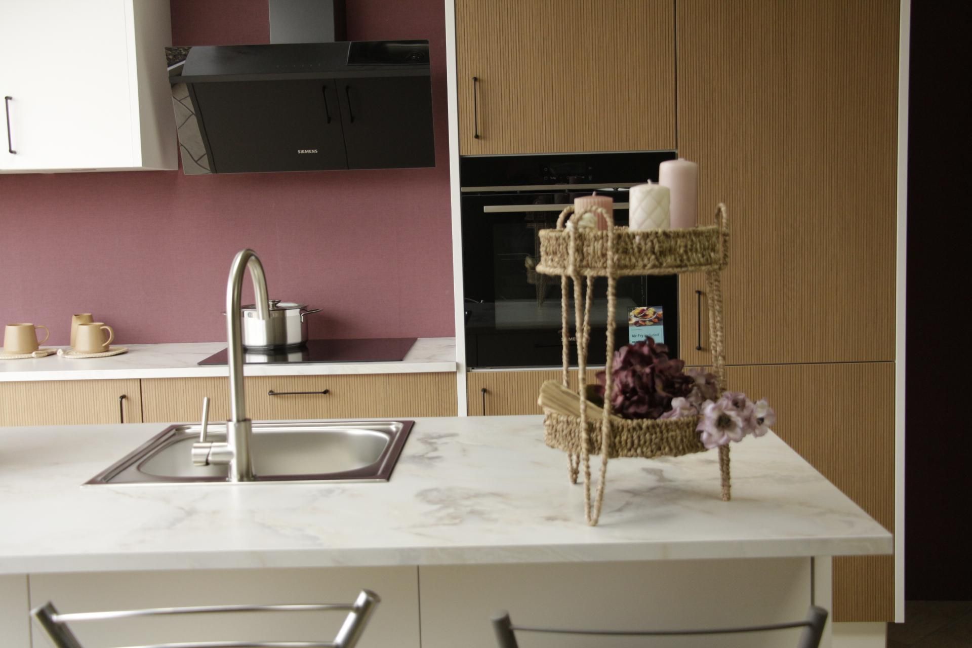 Keuken met roze achterwand, houten kasten en inbouwoven van J&S Budgetkeukens